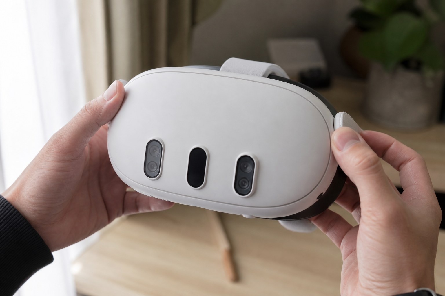 Hands holding a mixed reality VR headset with front-facing passthrough cameras